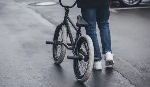 Cropped photo of boy walking with bmx bicycle on street
