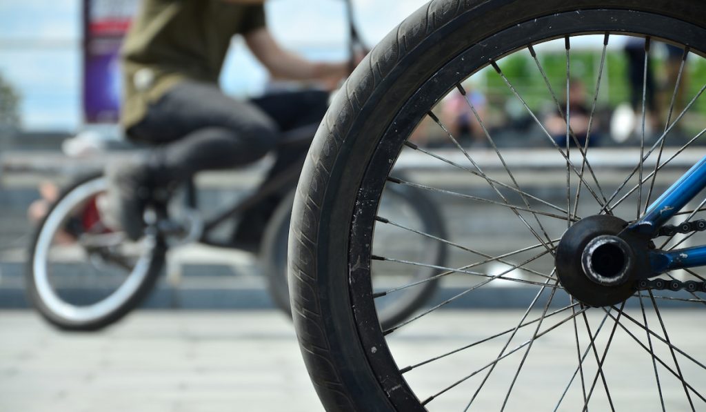 A BMX bike wheel against the backdrop of a blurred street with cycling riders
