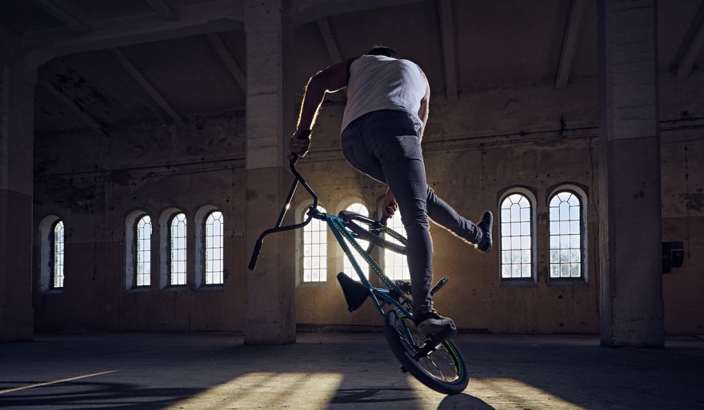 BMX stunts in a sunray indoor gothic hall.
