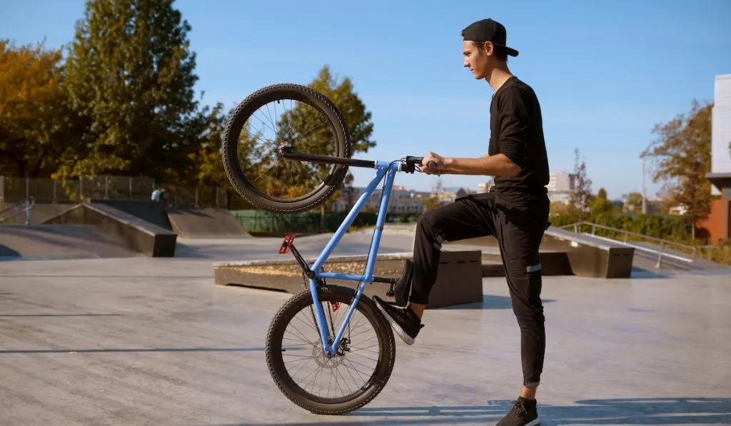 Male bmx biker doing trick, training in skatepark
