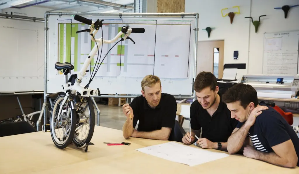 Three men discussing about a folding bicycle