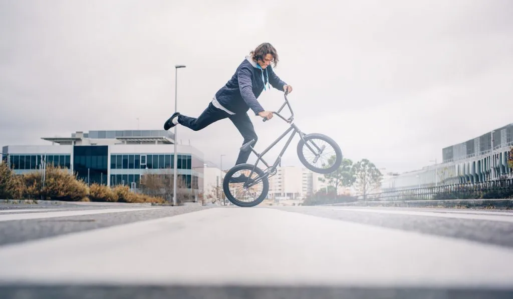 Young man practices with BMX bicycle.
