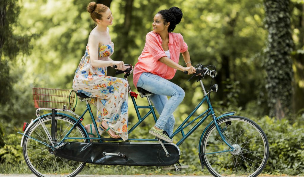 Young women riding on the tandem bicycle
