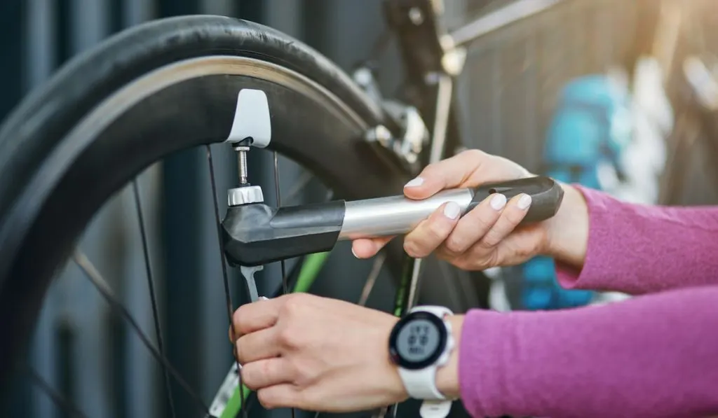 cropped photo of woman holding pump for inflating the tire of her bike