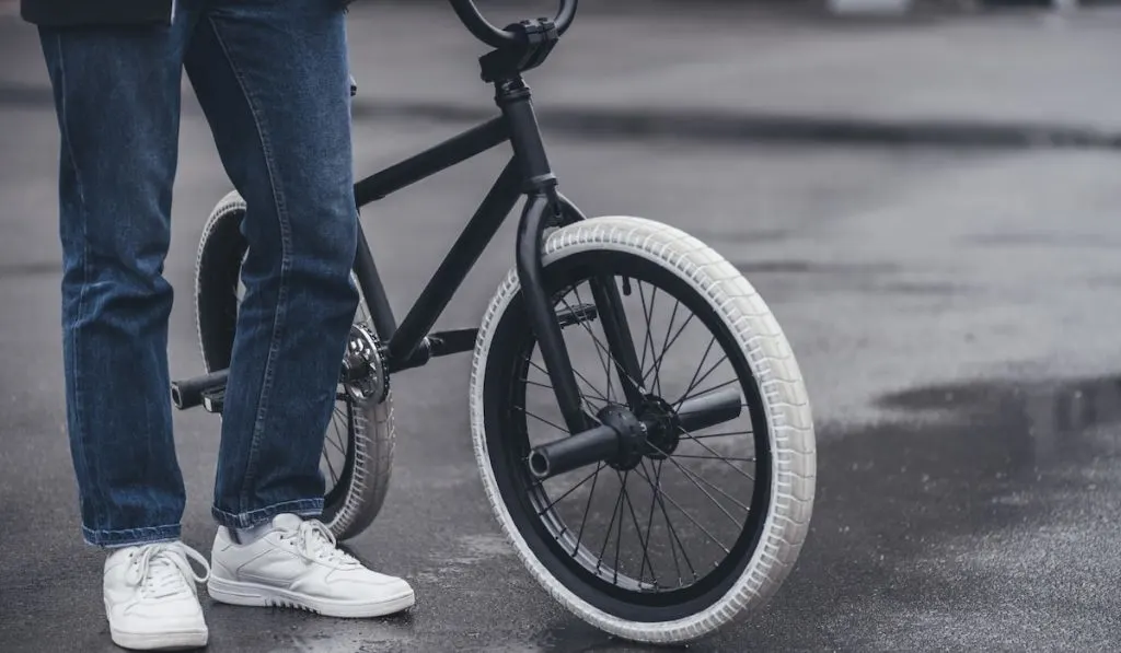 cropped shot of boy standing with bmx bicycle on street
