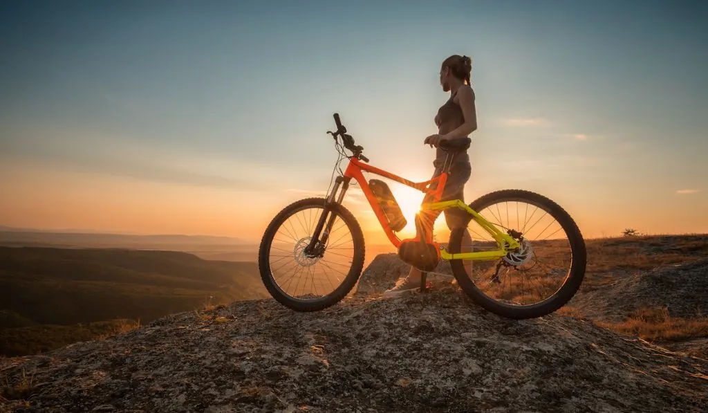 woman with her bike looking at beautiful sunset view